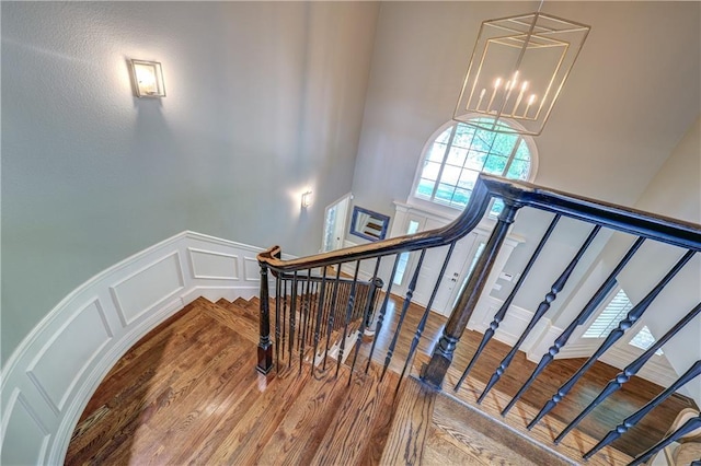 14911 Outlook Ln, Overland Park, KS 66223 - stairway with a chandelier, wood finished floors, a high ceiling, and a decorative wall