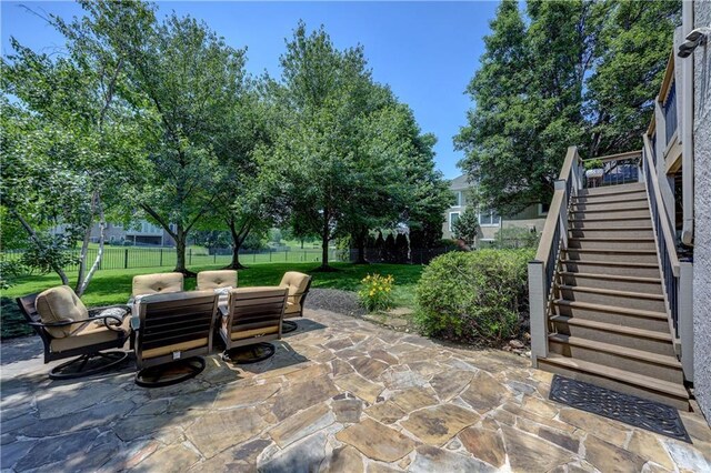 14911 Outlook Ln, Overland Park, KS 66223 - fenced backyard with stairs, outdoor dining space, and a patio area