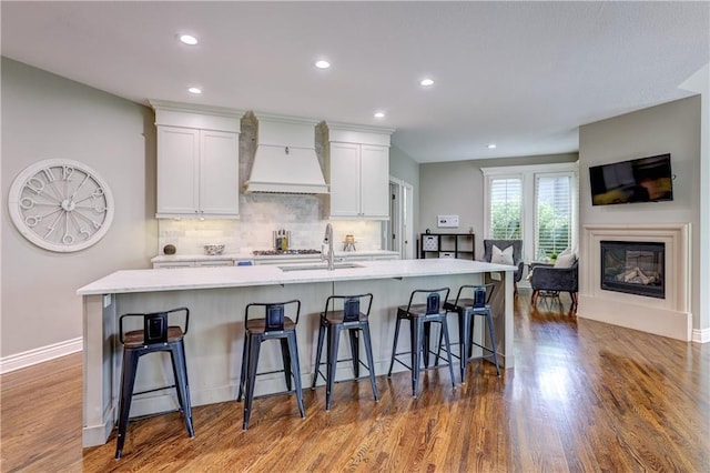 14911 Outlook Ln, Overland Park, KS 66223 - kitchen with custom exhaust hood, a large island with sink, white cabinets, wood finished floors, and recessed lighting