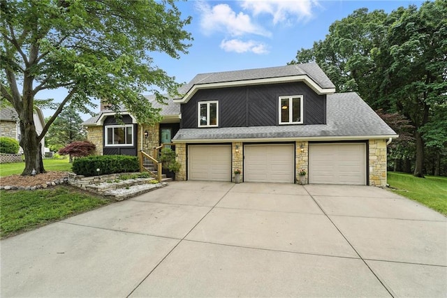 3437 N Wabash Ave, Kansas City, MO 64116 - split level home with stone siding, roof with shingles, a front lawn, and concrete driveway