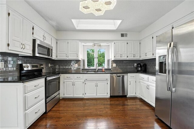 3437 N Wabash Ave, Kansas City, MO 64116 - kitchen featuring appliances with stainless steel finishes, dark countertops, white cabinets, and tasteful backsplash