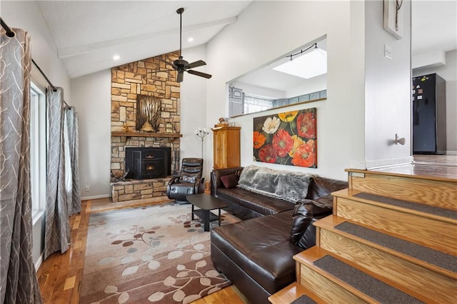 19109 Quinn Rd, Trimble, MO 64492 - living area with lofted ceiling, a stone fireplace, wood finished floors, a ceiling fan, and a skylight