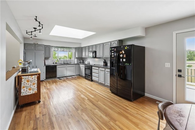 19109 Quinn Rd, Trimble, MO 64492 - kitchen featuring black appliances, gray cabinetry, a skylight, and a sink