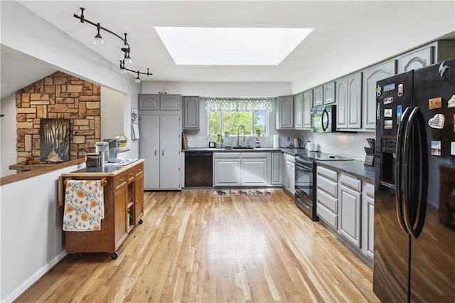 19109 Quinn Rd, Trimble, MO 64492 - kitchen with black appliances, a skylight, gray cabinetry, and rail lighting