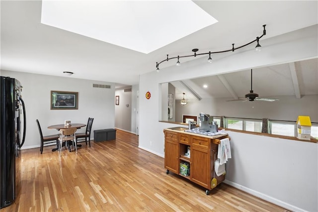 19109 Quinn Rd, Trimble, MO 64492 - kitchen featuring freestanding refrigerator, brown cabinets, ceiling fan, light wood-style flooring, and a skylight