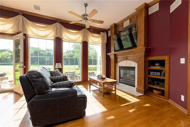 6501 N National Dr, Parkville, MO 64152 - living room featuring a tile fireplace, crown molding, a ceiling fan, light wood-type flooring, and baseboards