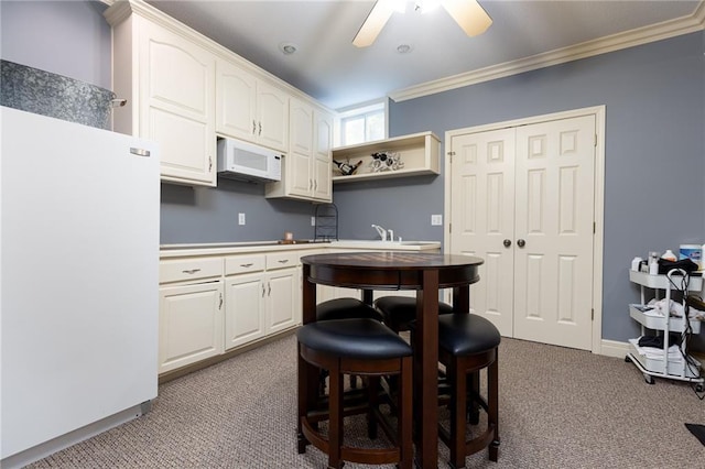 6501 N National Dr, Parkville, MO 64152 - kitchen with white appliances, carpet flooring, ornamental molding, white cabinets, and a ceiling fan