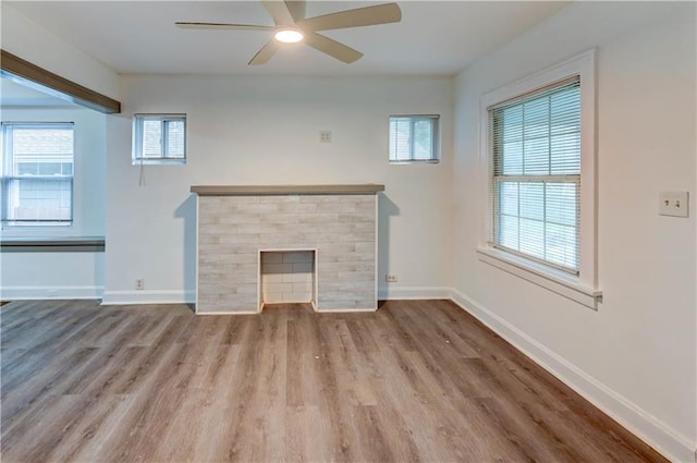 6117 Harrison St, Kansas City, MO 64110 - unfurnished living room with ceiling fan, wood finished floors, baseboards, and a fireplace