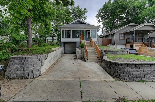 6117 Harrison St, Kansas City, MO 64110 - bungalow-style home featuring stairs, concrete driveway, an attached garage, and covered porch
