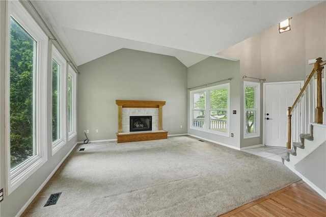 14876 S Summit St, Olathe, KS 66062 - unfurnished living room featuring plenty of natural light, carpet flooring, a tile fireplace, lofted ceiling, and stairs
