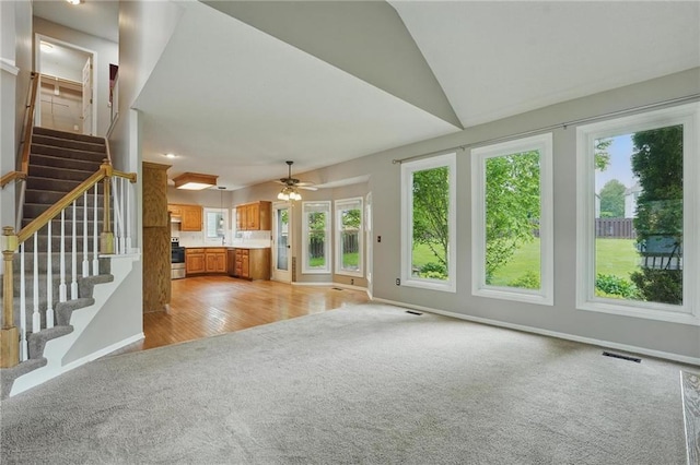 14876 S Summit St, Olathe, KS 66062 - unfurnished living room with light colored carpet, healthy amount of natural light, stairs, a ceiling fan, and lofted ceiling