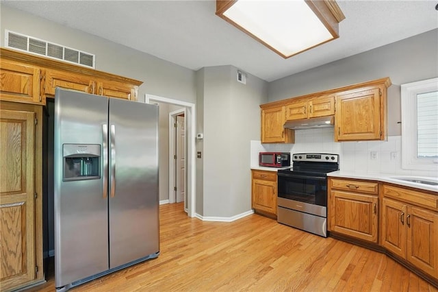 14876 S Summit St, Olathe, KS 66062 - kitchen with appliances with stainless steel finishes, light wood-style flooring, under cabinet range hood, tasteful backsplash, and light countertops