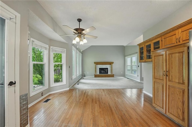 14876 S Summit St, Olathe, KS 66062 - unfurnished living room with a fireplace with raised hearth, lofted ceiling, healthy amount of natural light, and light wood finished floors