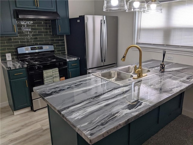 203 W 4th St, Holden, MO 64040 - kitchen with range with gas stovetop, freestanding refrigerator, under cabinet range hood, a sink, and decorative backsplash