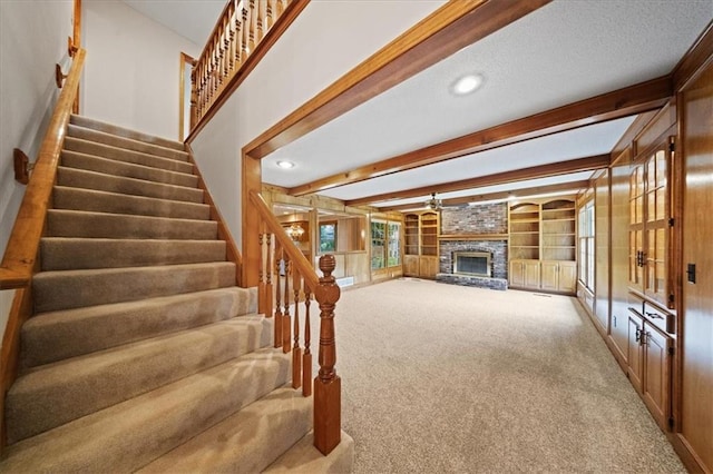 9509 W 116th Ter, Overland Park, KS 66210 - unfurnished living room with carpet, beam ceiling, stairway, a large fireplace, and recessed lighting