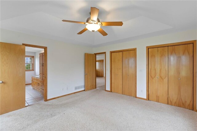 25549 Chieftain Rd, Lawrence, KS 66044 - unfurnished bedroom with light colored carpet, two closets, ensuite bathroom, baseboards, and a ceiling fan
