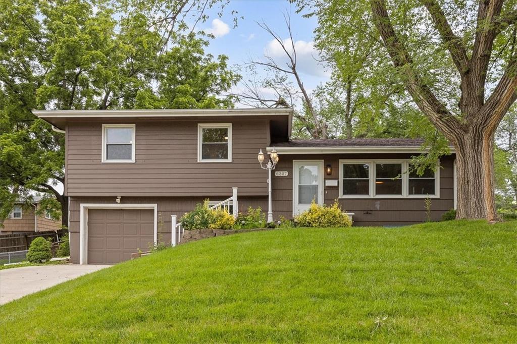 6307 N Wayne Ave, Kansas City, MO 64118 - split level home featuring a garage, a front yard, and concrete driveway