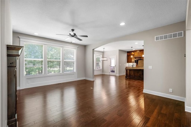 9154 Shady Bend Rd, Lenexa, KS 66227 - unfurnished living room featuring arched walkways, a ceiling fan, dark wood-style flooring, recessed lighting, and a textured ceiling