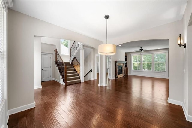 9154 Shady Bend Rd, Lenexa, KS 66227 - unfurnished living room with hardwood / wood-style flooring, a ceiling fan, a glass covered fireplace, and stairs