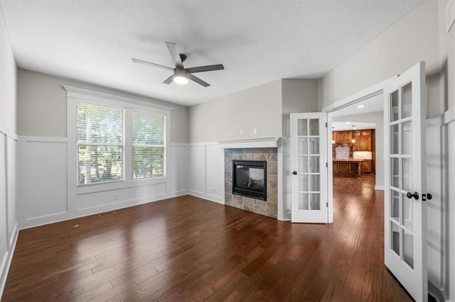 9154 Shady Bend Rd, Lenexa, KS 66227 - unfurnished living room featuring french doors, ceiling fan, wood finished floors, a tile fireplace, and wainscoting