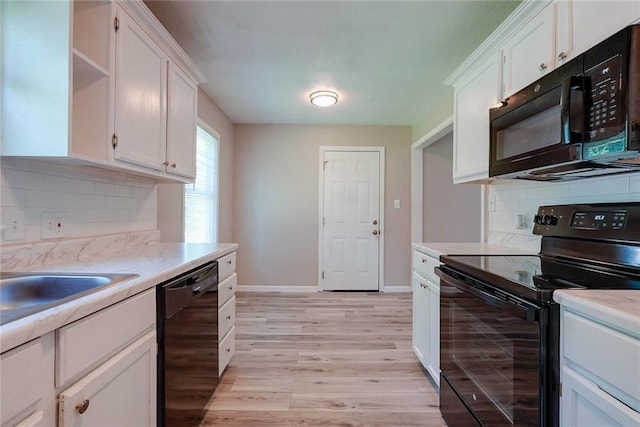 3512 Harvard Ave, Independence, MO 64052 - kitchen featuring black appliances, white cabinetry, light countertops, and light wood-type flooring