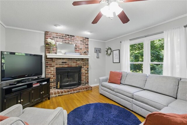 11409 Riley St, Overland Park, KS 66210 - living room with light wood-type flooring, crown molding, a brick fireplace, a ceiling fan, and a textured ceiling