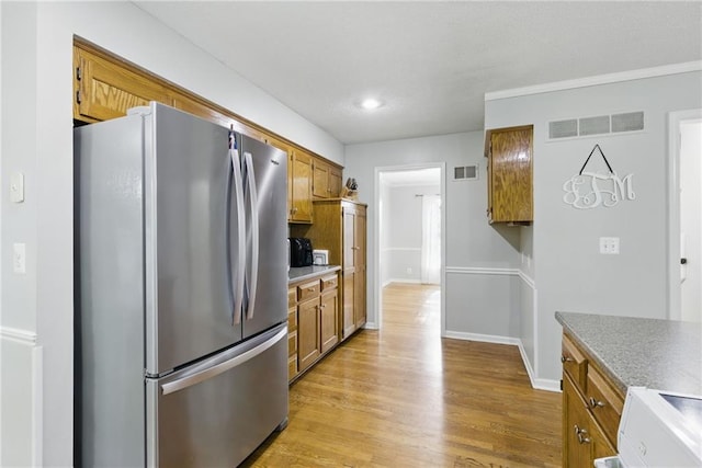11409 Riley St, Overland Park, KS 66210 - kitchen with freestanding refrigerator, brown cabinets, light wood-type flooring, range, and light countertops