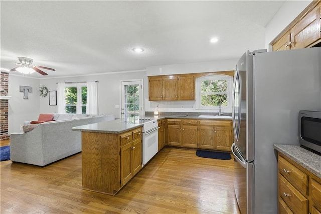 11409 Riley St, Overland Park, KS 66210 - kitchen featuring stainless steel appliances, brown cabinetry, a peninsula, light wood-style floors, and ceiling fan