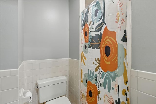 11409 Riley St, Overland Park, KS 66210 - bathroom featuring tile walls, wainscoting, and a shower with curtain