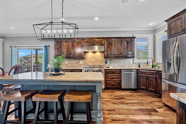 17746 W 165th Pl, Olathe, KS 66062 - kitchen with appliances with stainless steel finishes, range hood, a breakfast bar, plenty of natural light, and ornamental molding