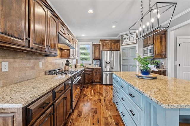 17746 W 165th Pl, Olathe, KS 66062 - kitchen with appliances with stainless steel finishes, under cabinet range hood, crown molding, dark wood finished floors, and decorative backsplash