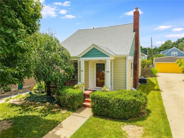4930 Holly St, Kansas City, MO 64112 - bungalow-style home with roof with shingles, a front yard, and a chimney