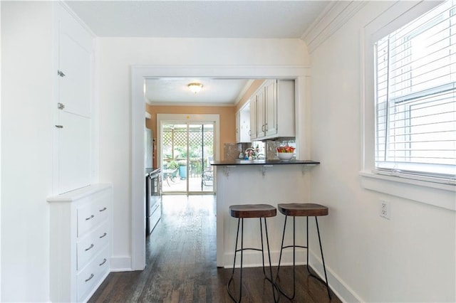 4930 Holly St, Kansas City, MO 64112 - kitchen featuring a kitchen breakfast bar, dark wood-style flooring, white cabinets, dark countertops, and a peninsula
