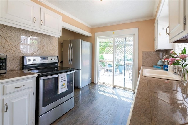 4930 Holly St, Kansas City, MO 64112 - kitchen featuring stainless steel appliances, tile countertops, decorative backsplash, and crown molding