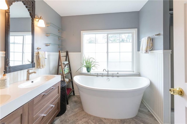 4930 Holly St, Kansas City, MO 64112 - full bathroom with wainscoting, a freestanding tub, double vanity, and a decorative wall