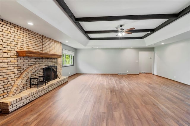 2207 N 154th Ter, Basehor, KS 66007 - unfurnished living room with wood finished floors, a ceiling fan, a fireplace, beamed ceiling, and recessed lighting