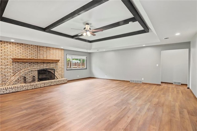 2207 N 154th Ter, Basehor, KS 66007 - unfurnished living room with ceiling fan, a brick fireplace, recessed lighting, light wood-style flooring, and a tray ceiling