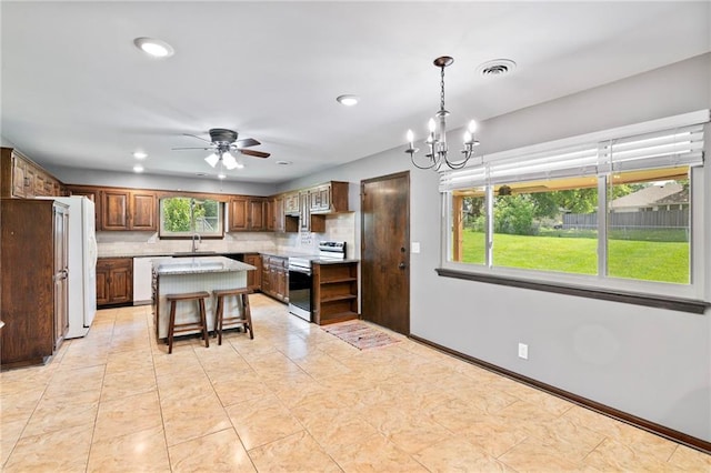 2207 N 154th Ter, Basehor, KS 66007 - kitchen featuring stainless steel electric range oven, light countertops, a chandelier, a center island, and decorative backsplash