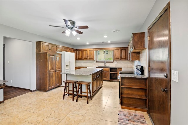 2207 N 154th Ter, Basehor, KS 66007 - kitchen featuring white fridge with ice dispenser, ceiling fan, light stone counters, open shelves, and a center island