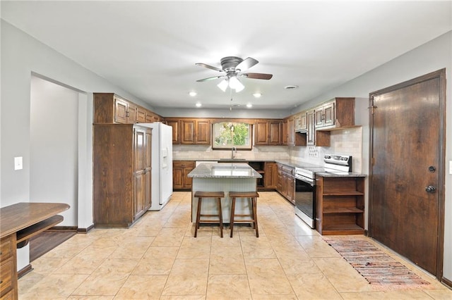 2207 N 154th Ter, Basehor, KS 66007 - kitchen featuring stainless steel range with electric cooktop, white refrigerator with ice dispenser, ceiling fan, decorative backsplash, and a center island