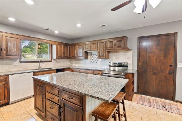 2207 N 154th Ter, Basehor, KS 66007 - kitchen featuring white dishwasher, light tile patterned flooring, a kitchen bar, tasteful backsplash, and light stone counters