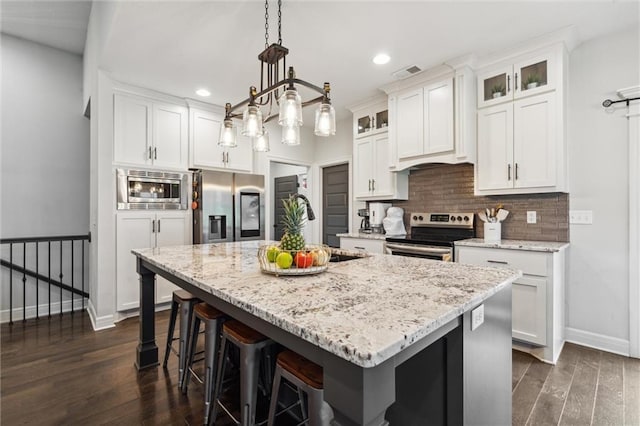1402 NW Red Oak Ct, Grain Valley, MO 64029 - kitchen featuring appliances with stainless steel finishes, recessed lighting, white cabinetry, dark wood-style flooring, and an island with sink