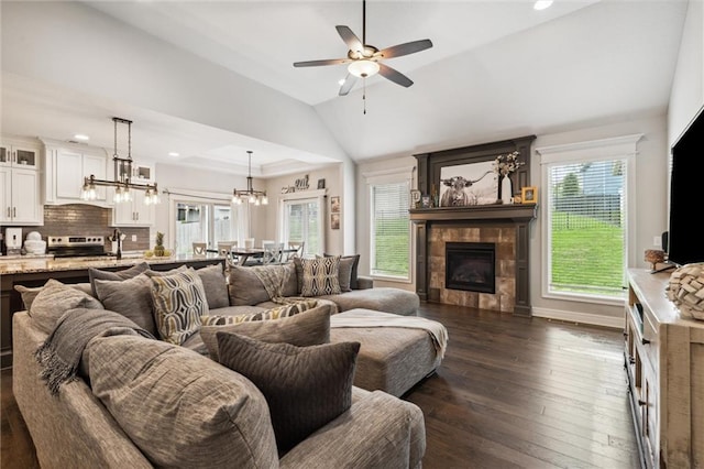 1402 NW Red Oak Ct, Grain Valley, MO 64029 - living area with lofted ceiling, dark wood-type flooring, ceiling fan, a tile fireplace, and a chandelier