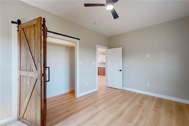 350 NW 1201st Rd, Holden, MO 64040 - unfurnished bedroom with a barn door, light wood finished floors, a ceiling fan, and a closet