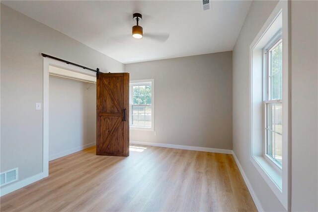 350 NW 1201st Rd, Holden, MO 64040 - unfurnished bedroom with light wood-type flooring, a barn door, and a ceiling fan