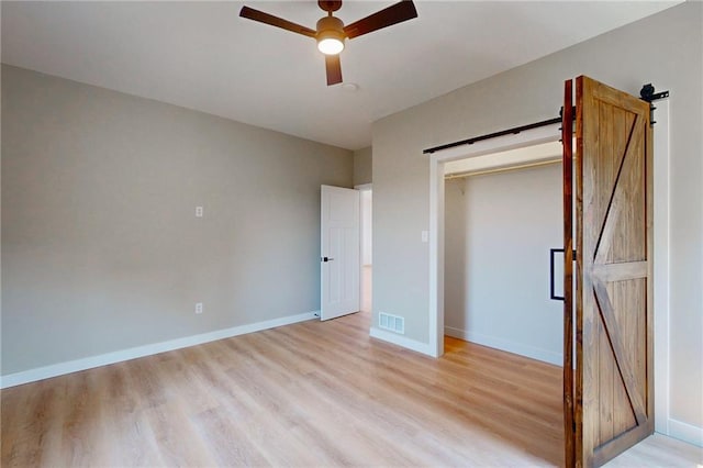 350 NW 1201st Rd, Holden, MO 64040 - unfurnished bedroom with a barn door, light wood-style floors, and ceiling fan