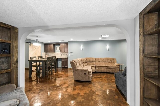 600 SW Gentry Ln, Lees Summit, MO 64081 - living area featuring arched walkways, a barn door, concrete floors, a textured ceiling, and recessed lighting