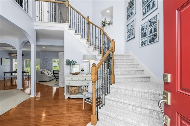 600 SW Gentry Ln, Lees Summit, MO 64081 - entrance foyer featuring wood finished floors, arched walkways, stairway, a high ceiling, and crown molding