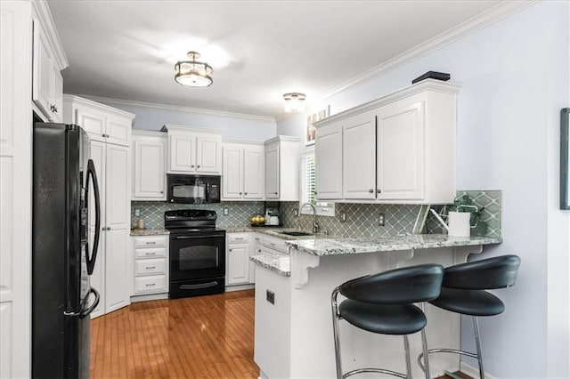 600 SW Gentry Ln, Lees Summit, MO 64081 - kitchen featuring black appliances, a peninsula, a kitchen bar, tasteful backsplash, and ornamental molding