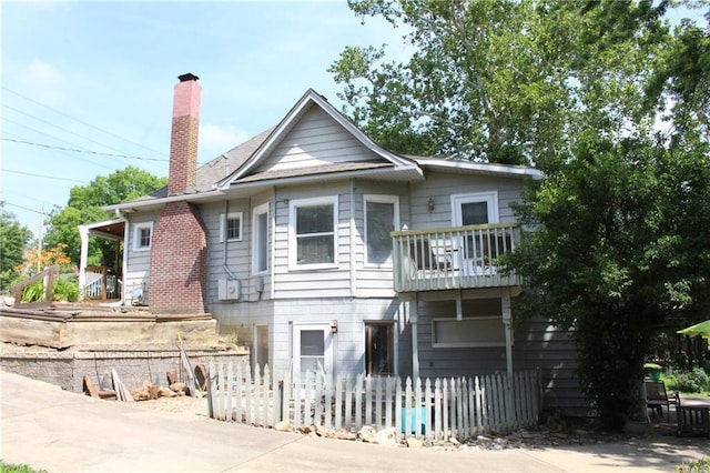 421 N Nettleton Ave, Bonner Springs, KS 66012 - view of front of house featuring a balcony, a fenced front yard, and a chimney